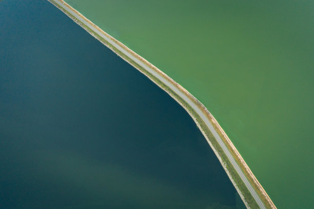 美丽的道路，一边是湖，另一边是森林。图片下载