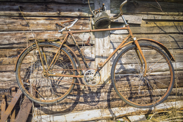 一辆很旧、生锈的自行车挂在一座旧木屋的墙上图片下载
