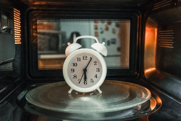 早上6点的白色闹钟在微波炉里面，里面的照片。时间流逝的概念图片下载