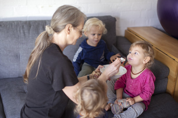 一位年长的母亲在家里和她的三胞胎玩。图片下载