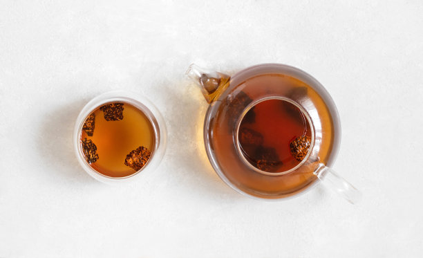 在一个玻璃茶壶和一个碗在一个白色的背景上喝茶加蘑菇。时尚健康的饮料。俯视图，平放。图片下载