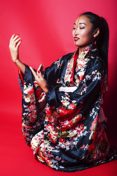 年轻漂亮的艺妓在红色背景摆姿势的和服，东方的概念图片下载