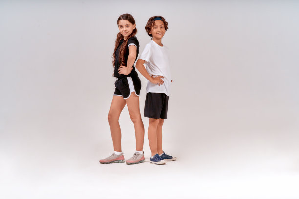 孩子们参加运动。两名青少年，可爱的男孩和女孩穿着运动服看着镜头，微笑着，在灰色背景下摆出孤立的姿势图片下载
