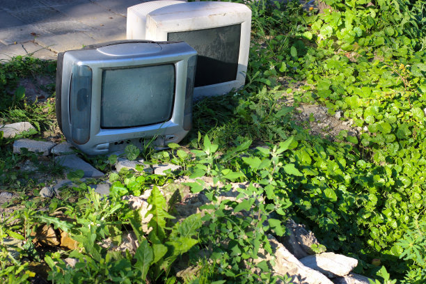 象征着一个时代的结束。台灯电视和电脑显示器被扔进了旧岩石和草地之间的荒地。图片下载