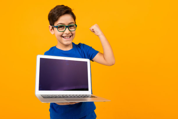 快乐的白人男孩显示笔记本电脑屏幕与模型在黄色工作室背景与复制空间图片下载