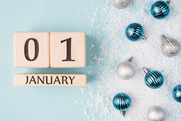 新年的概念。上面俯瞰的照片木制立方体显示新年的第一天孤立的蓝色背景与雪和小玩意图片下载