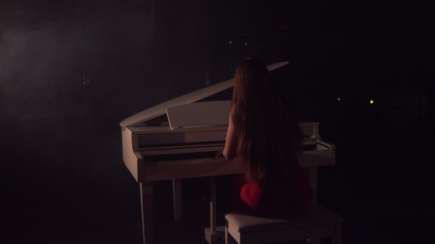 4K女钢琴家在美丽的大钢琴舞台上演奏的视频。一个女人在音乐厅里弹钢琴。舞台灯光和灯光雾的背景图片下载