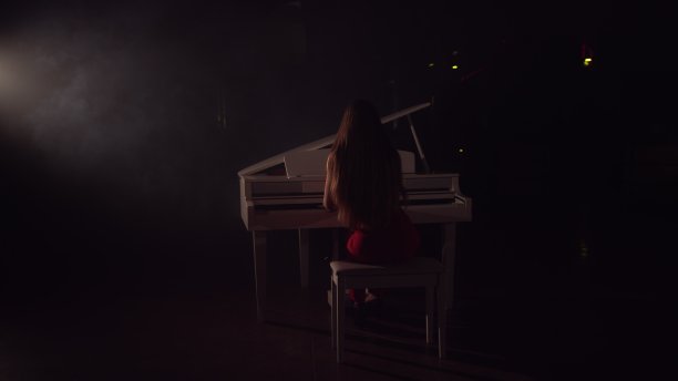 4K女钢琴家在美丽的大钢琴舞台上演奏的视频。一个女人在音乐厅里弹钢琴。舞台灯光和灯光雾的背景图片下载