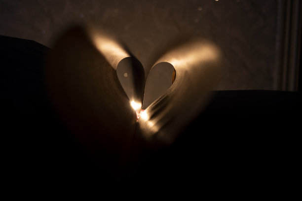 浪漫的黑色背景。心在书中，蜡烛在背景。特写与选择性焦点图片下载