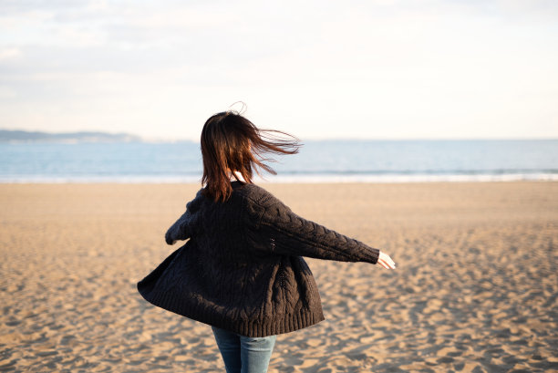 快乐的年轻女子在海滩上翩翩起舞图片下载