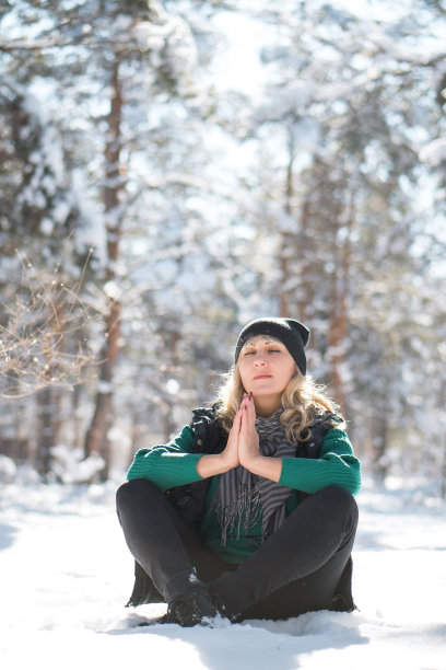 女人坐在冬天的森林里祈祷。图片下载