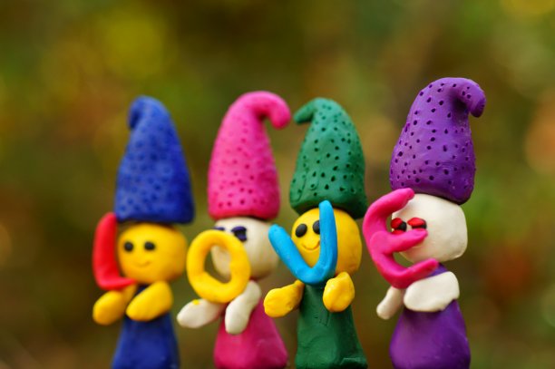 四个用橡皮泥制成的童话故事中的小矮人在森林里的彩色背景上。图片下载