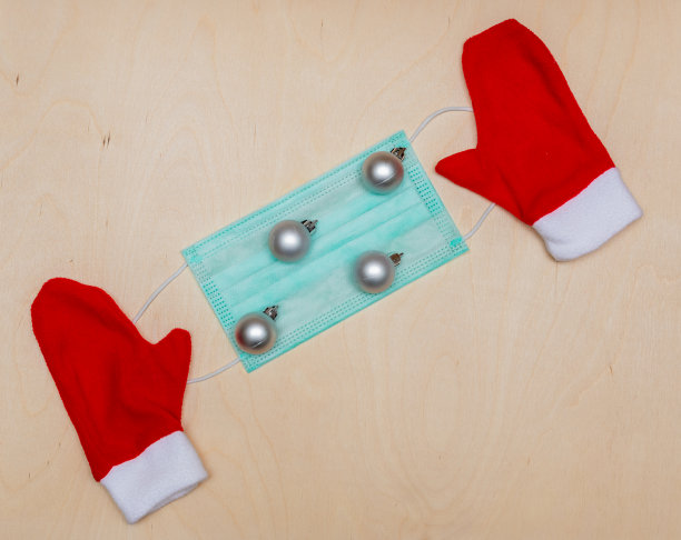 圣诞组成。银色的圣诞玩具，红色的圣诞老人手套和木制背景上的医用防护口罩。新2021年。大流行,冠状病毒。复制空间，俯视图，平铺。图片下载
