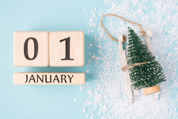 新年是这里的概念。顶部上方俯瞰照片的木立方体显示的第一天的一年和小圣诞树在雪橇上孤立的浅蓝色背景与雪图片下载