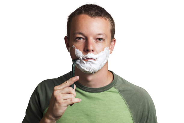 一个脸颊上有剃须泡沫的漂亮年轻人，手里拿着剃刀图片下载