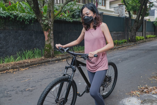 戴口罩的中国妇女带着自行车回家图片下载