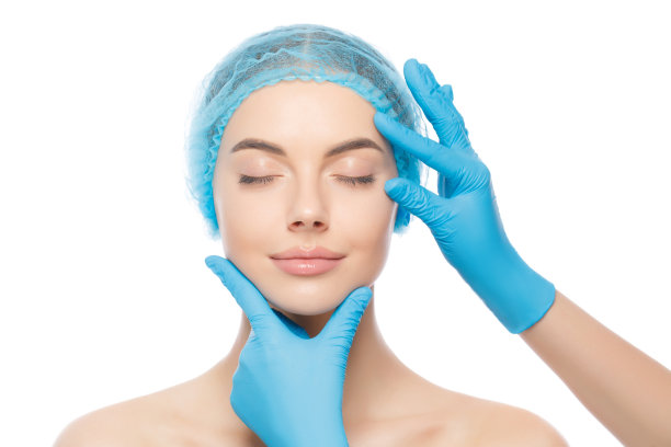 美丽的女子戴着医疗帽，在治疗前由美容诊所医生戴着手套检查，隔离在白色背景上图片下载