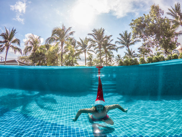 戴着圣诞老人帽在游泳池跳水的男人图片下载