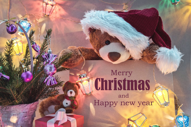 圣诞贺卡与泰迪熊礼物和童话灯花环。图片下载