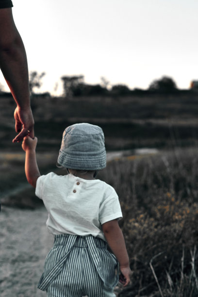 一个孩子牵着一个大人的手走在乡间小路上。夏天。图片下载