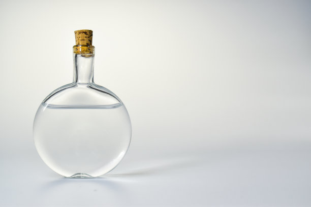 灯光背景上的空玻璃瓶。香水和化妆品的容器图片下载