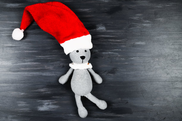 编织玩具兔子圣诞帽在深灰色的木制背景。空间的文本图片下载