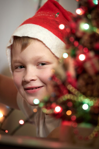 可爱的小男孩装饰圣诞树。圣诞节和新年的装饰图片下载