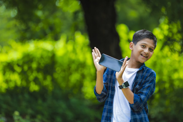 童年，科技和人的概念——印度可爱的学校男孩展示黑屏智能手机图片下载