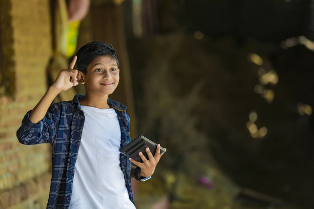年轻的印度可爱的孩子拿着智能手机图片下载