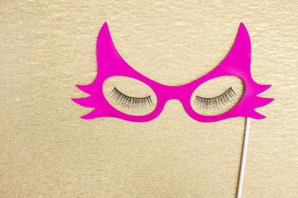 粉色的纸面具和金色背景的假睫毛。图片下载