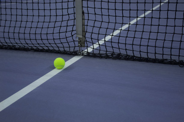 在蓝色网球场的网球线上放置的网球图片下载