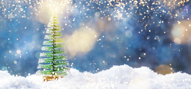 小圣诞树玩具在雪堆里，冬季新年的概念。蓝色背景，灯光和雪花的节日作文图片下载