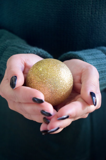 两只手拿着一个金色的圣诞小玩意儿图片下载