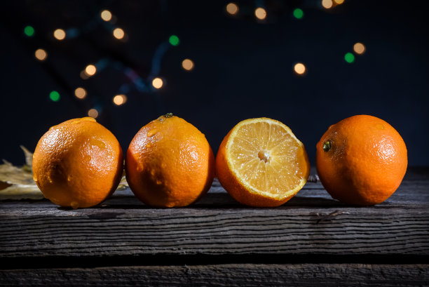 谷仓木板上的一排橙色小柑橘，背景灯在黑色背景上图片下载