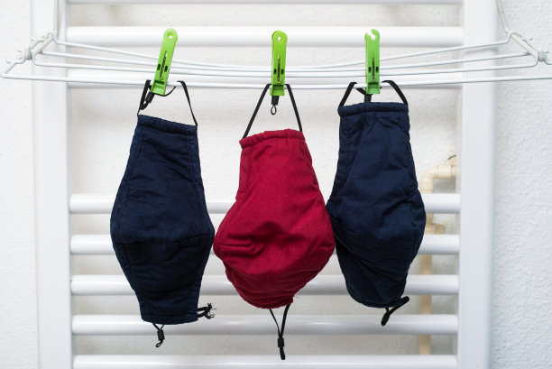 2019冠状病毒病大流行期间，清洗后挂在衣架上的织物口罩图片下载