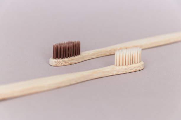 两把可降解的竹子牙刷，米色背景。图片下载