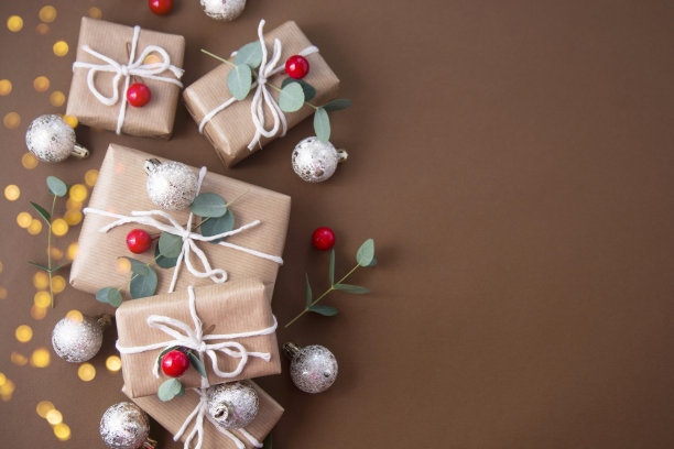 圣诞节的抽象背景。用牛皮纸包裹的礼品盒，上面装饰着桉树、小装饰品和散焦灯。图片下载