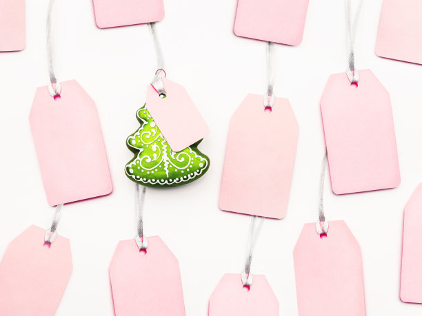 许多清楚的粉红色标签和装饰圣诞树在白色的背景。银色丝线上迷人的标签和复制空间。新年的象征是销售和购物。俯视图，平放。图片下载