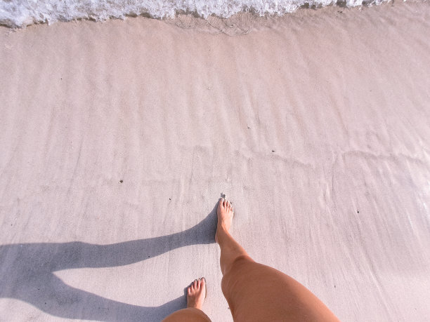 女孩在海边散步。美丽的古铜色女性的腿图片下载