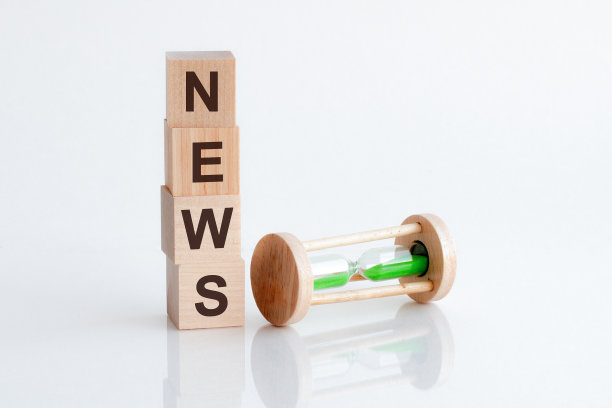 一个沙漏的特写，旁边是带有文本新闻的木块图片下载