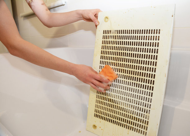 一个女人正在用海绵擦拭浴缸里的厨房过滤网。图片下载