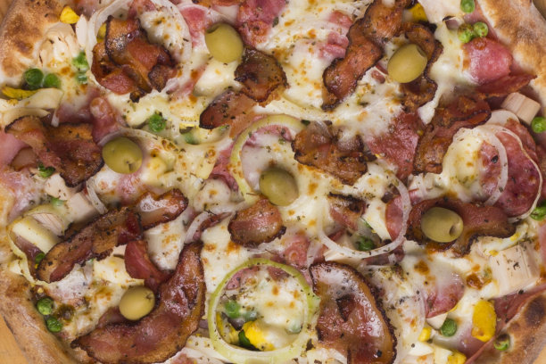 葡萄牙披萨，由火腿、豌豆蛋、棕榈心、意大利辣香肠、洋葱、马苏里拉奶酪和培根制成。美食的微距摄影。披萨餐厅图片。图片下载