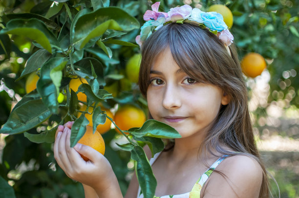 漂亮女孩对着有机橙树摆姿势图片下载