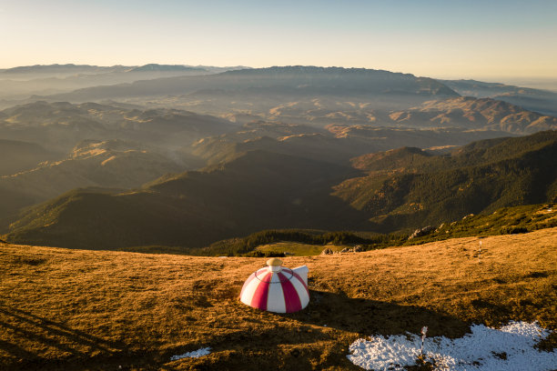 这是一个美丽的秋日，在罗马尼亚布加勒斯特山脉2170米高的地方，一个徒步旅行者观看日落的无人机照片图片下载