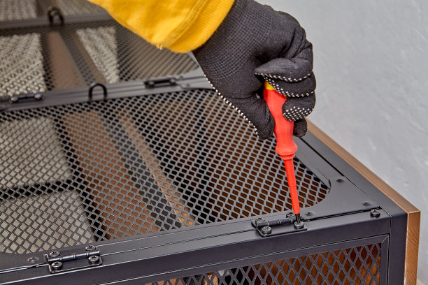 杂工在组装现代货架的同时拧上家具门铰链。图片下载