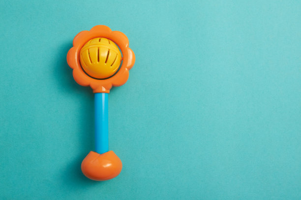 亮黄色和蓝色手柄的塑料玩具拨浪鼓。塑料复古喋喋不休。蓝色背景的婴儿玩具。平的。副本的空间。图片下载