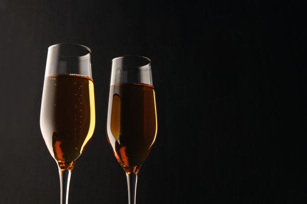 两杯香槟，黑色背景上的葡萄酒，右边文字的位置，复制空间。新年和圣诞节的背景图片下载