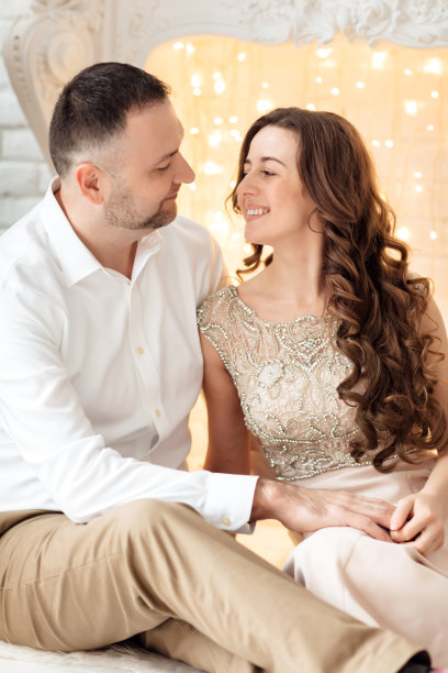 圣诞快乐。年轻夫妇在壁炉附近庆祝圣诞节。幸福的年轻夫妇坐在家里的圣诞树旁。年轻夫妇在圣诞节期间拥抱的照片图片下载