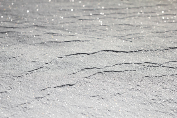 雪白的背景。雪的质地。闪亮的雪与散景和模糊的背景特写。白色的白雪覆盖的领域。雪景微距照片。图片下载