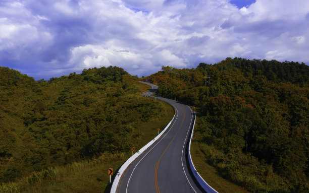 鸟瞰图的山路与汽车，橙色森林日落在秋天的欧洲图片下载